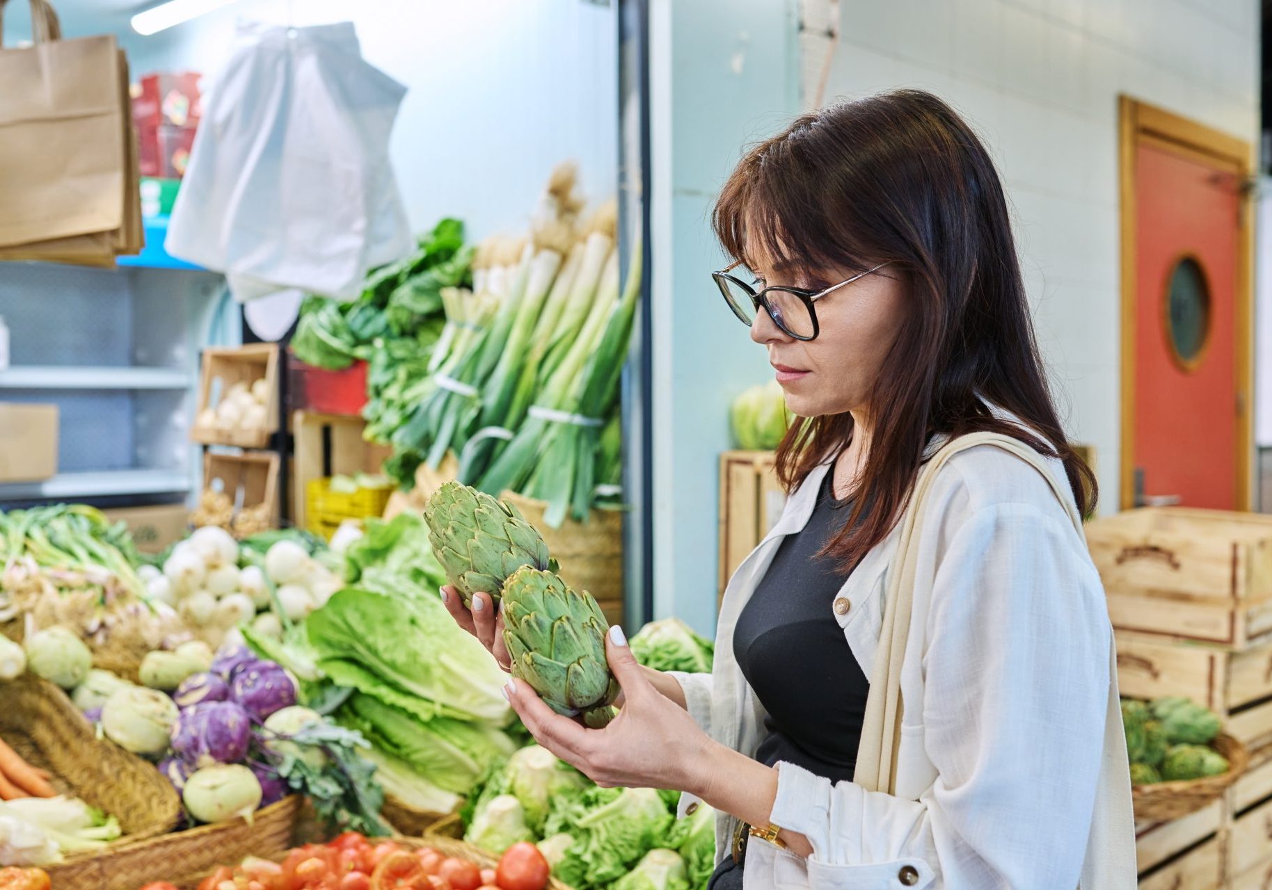 donna che osserva carciofi mentre fa spesa