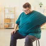 uomo obeso seduto su sgabello