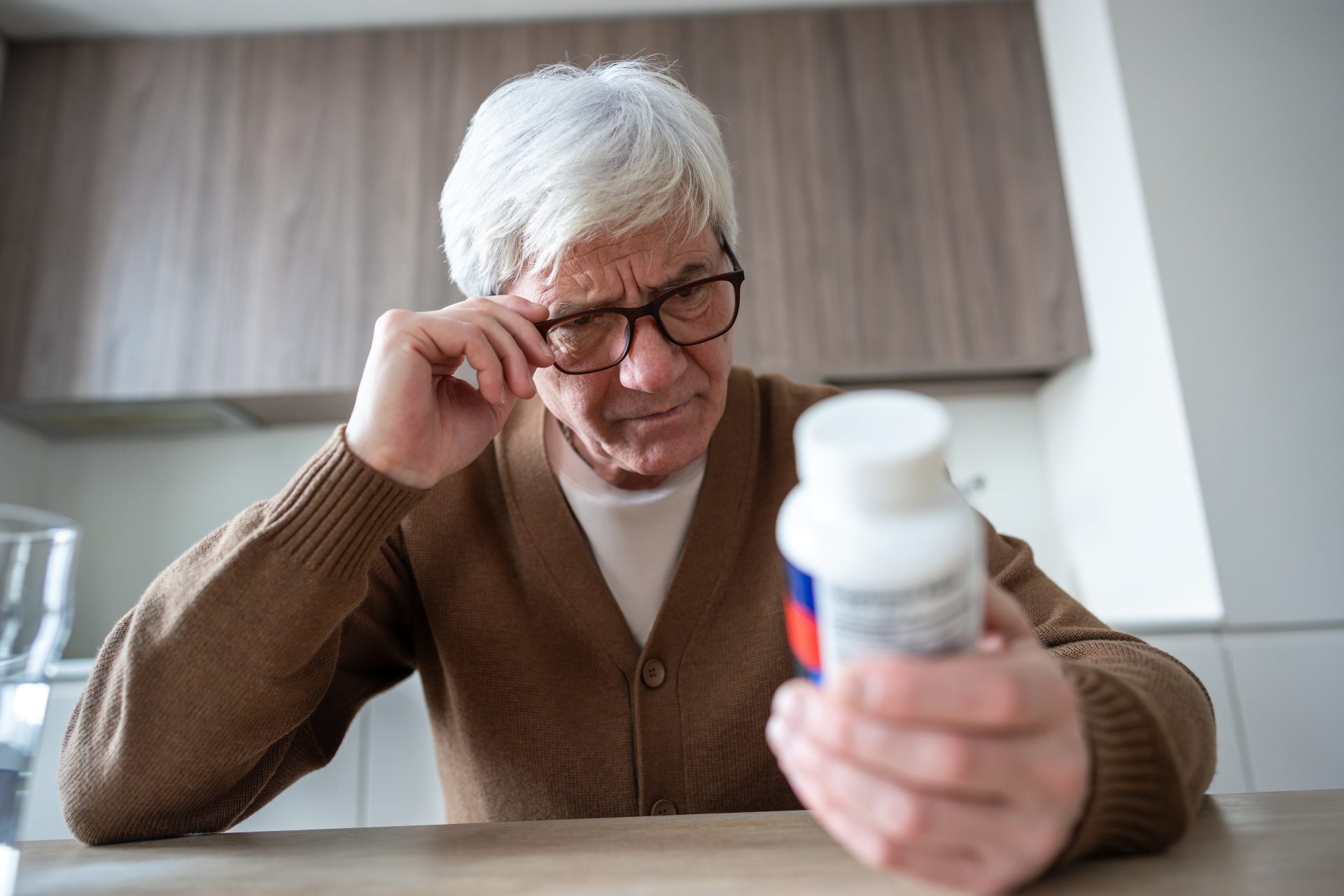 uomo anziano osserva confezione di medicinali