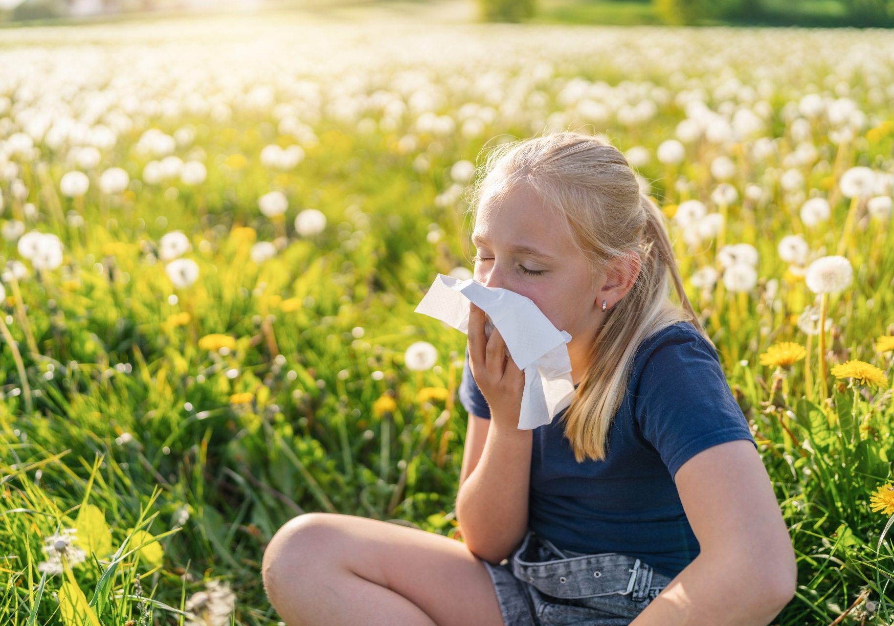 bambina in un prato soffia il naso per allergia alle graminacee