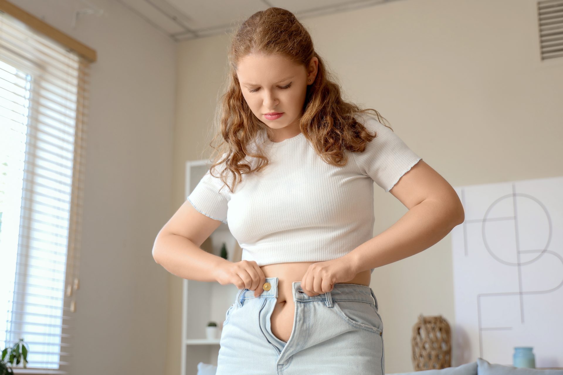 ragazza fatica a indossare paio di jeans