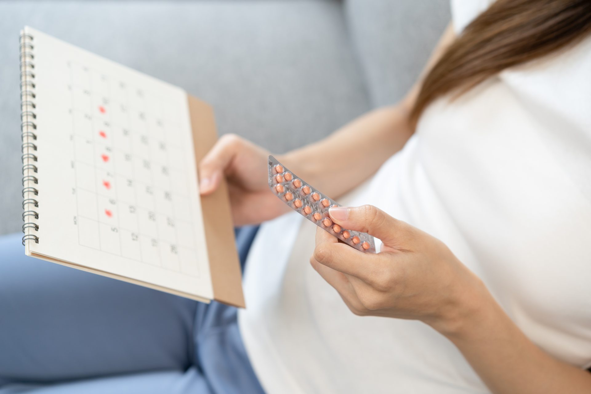 donna tiene in mano blister di pillola anticoncezionale e controlla calendario 