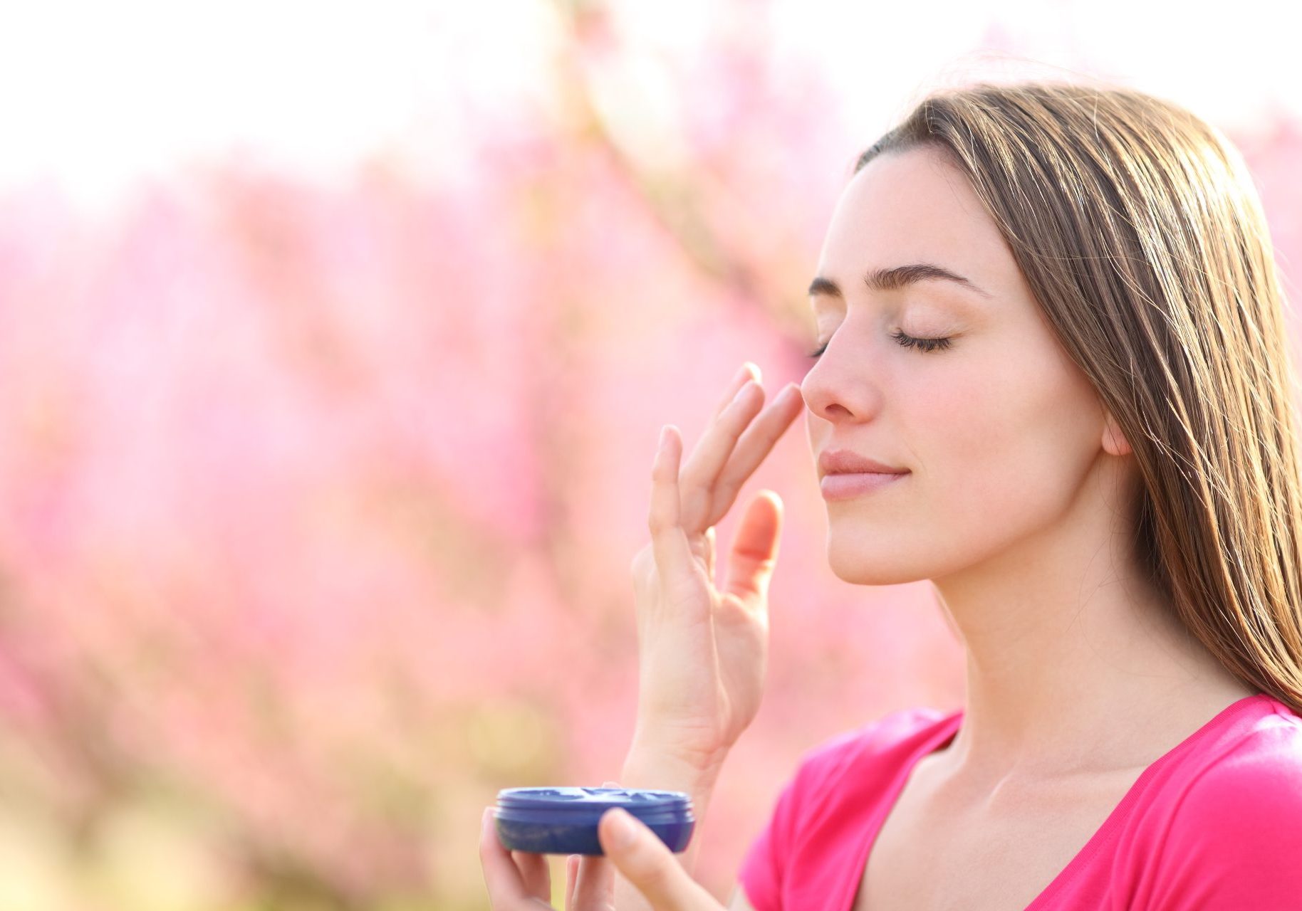 protezione-solare_cover giovane donna applica protezione solare all'aperto