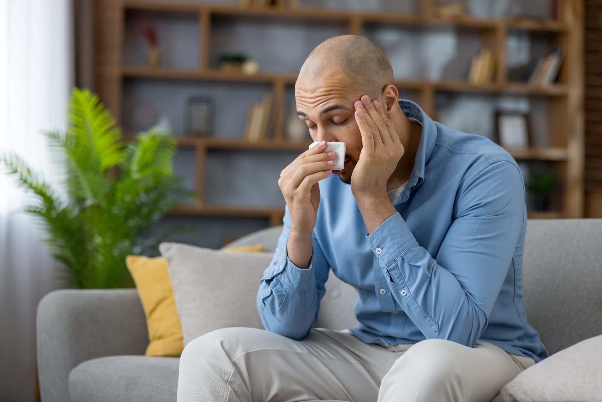 uomo sul divano si soffia il naso