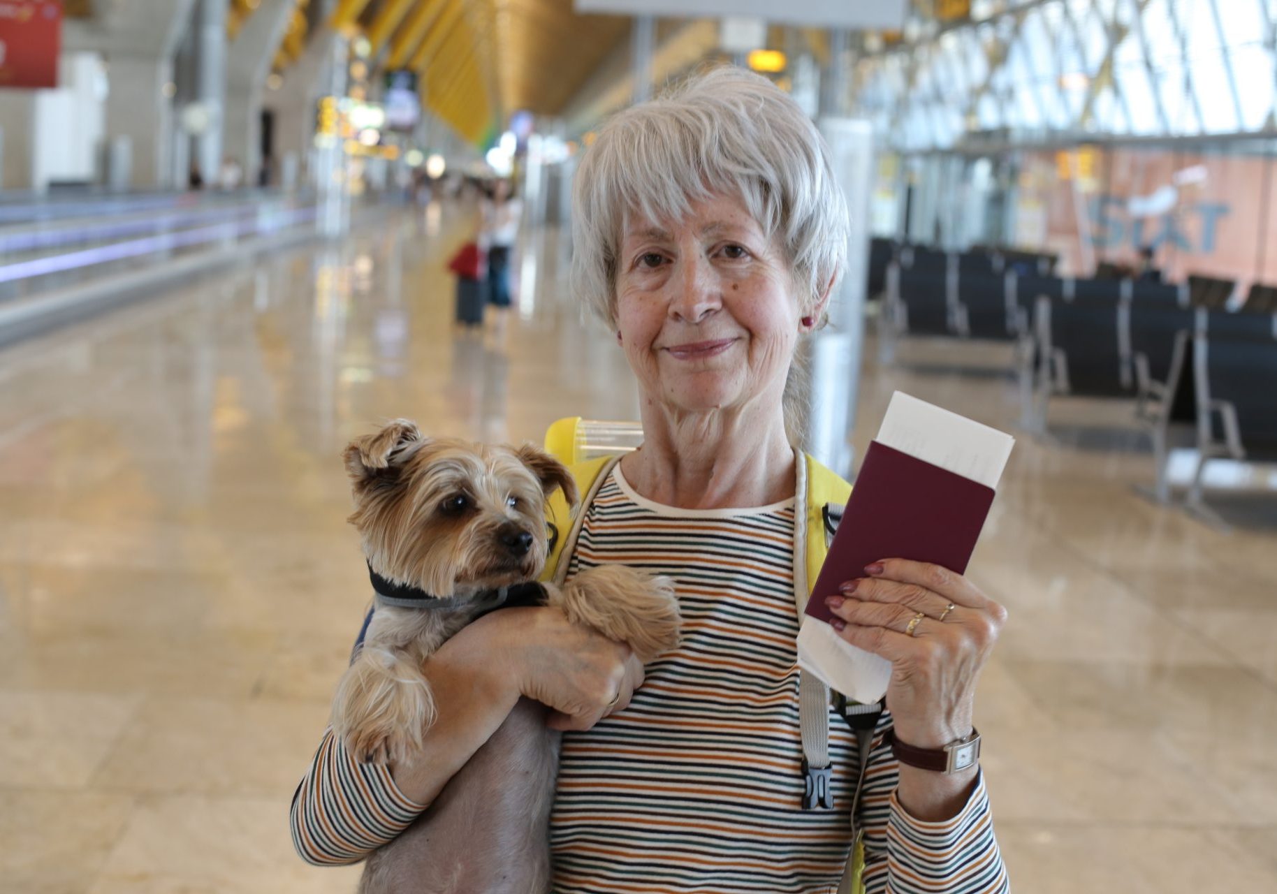 vaccinazioni-animali-viaggio donna anziana con cagnolino in braccio e passaporto in mano