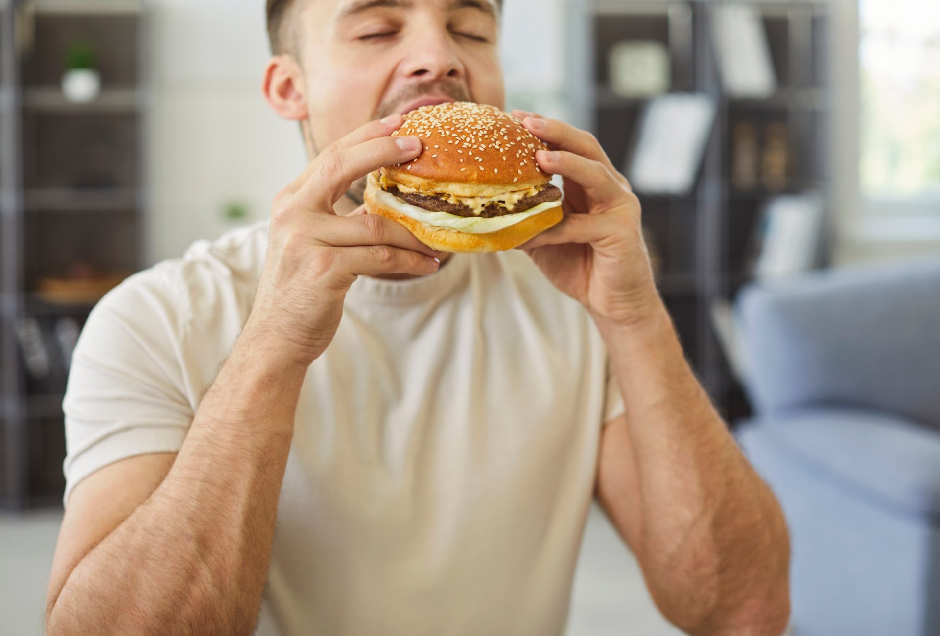 uomo mangia panino farcito con hamburger