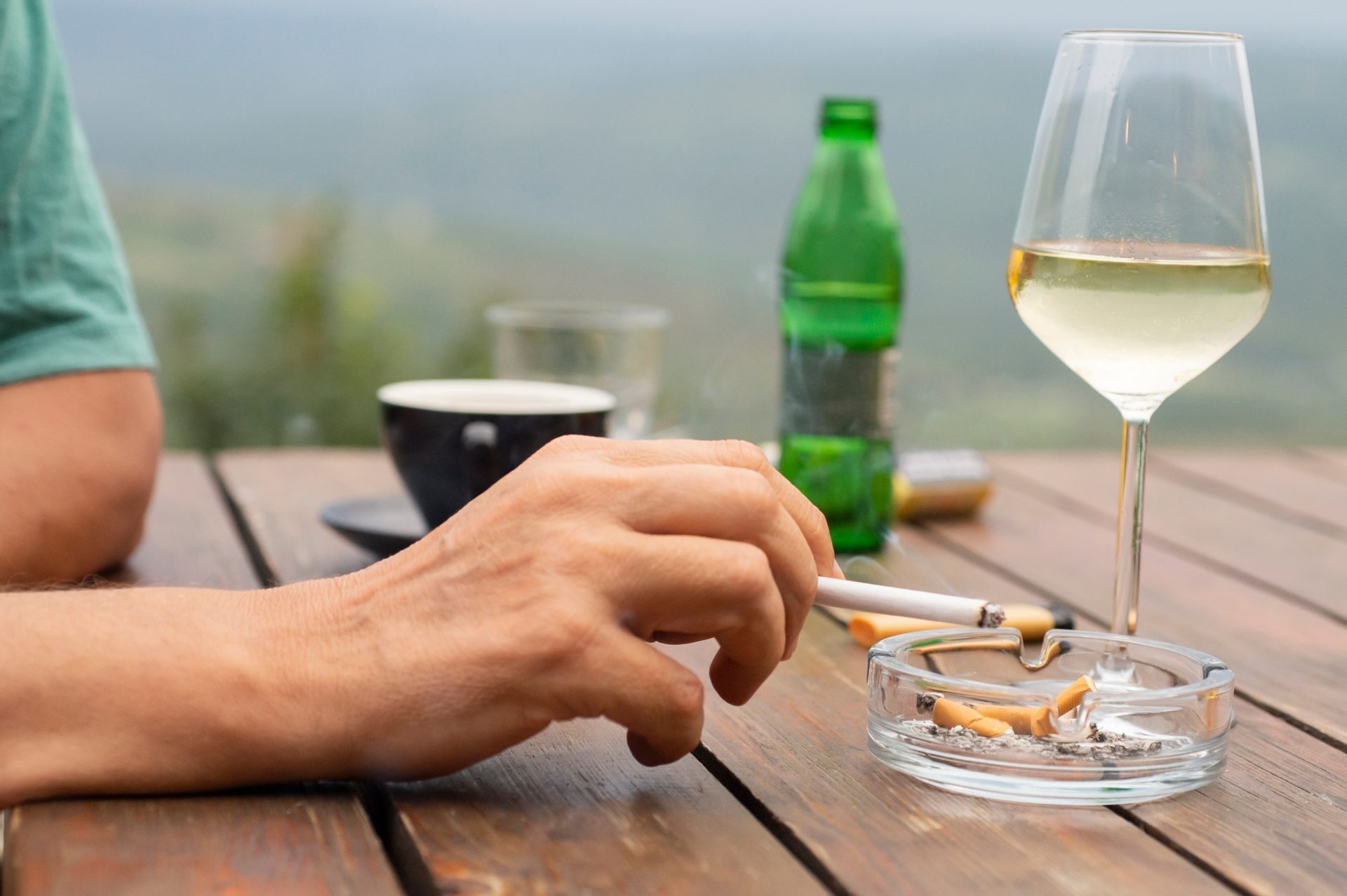 uomo fuma con calice di vino