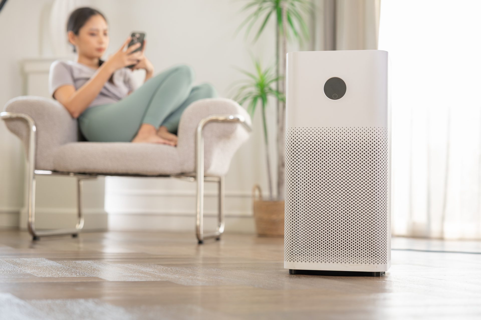 donna usa smartphone su poltrona vicino a purificatore d'aria