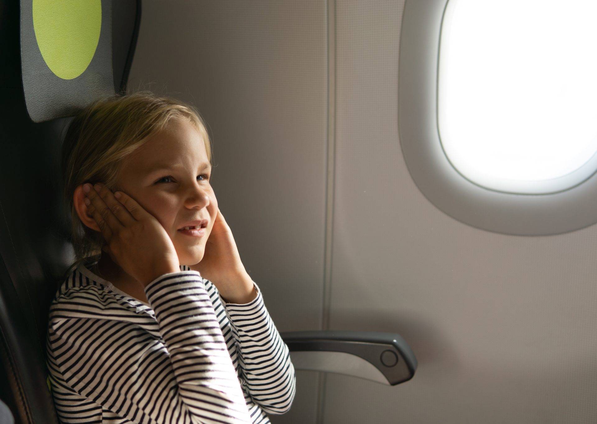 bambina in aereo con orecchie tappate