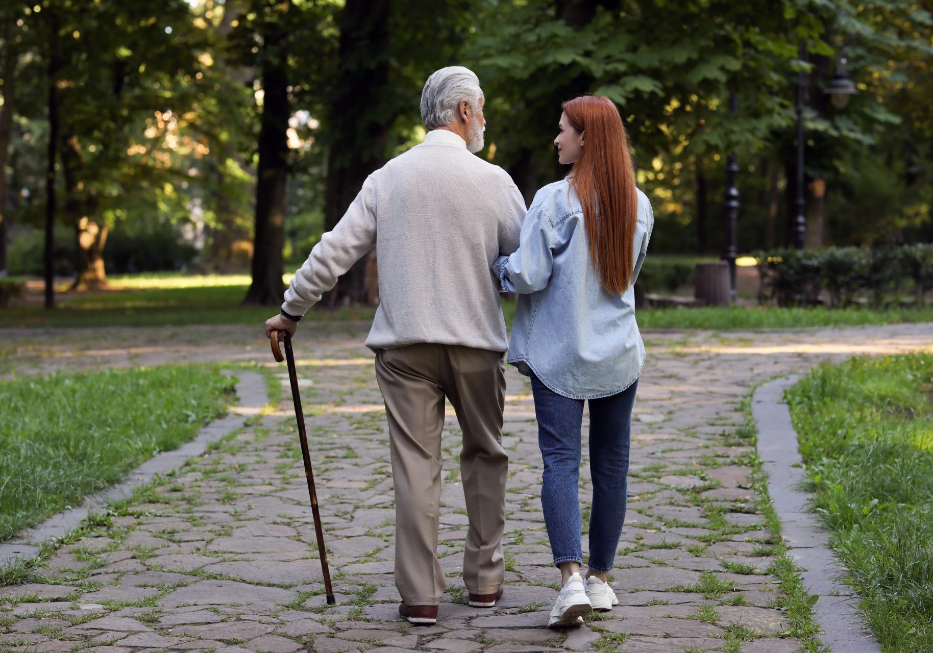 anziano-non-autosufficiente giovane donna accompagna anziano con bastone da passeggio