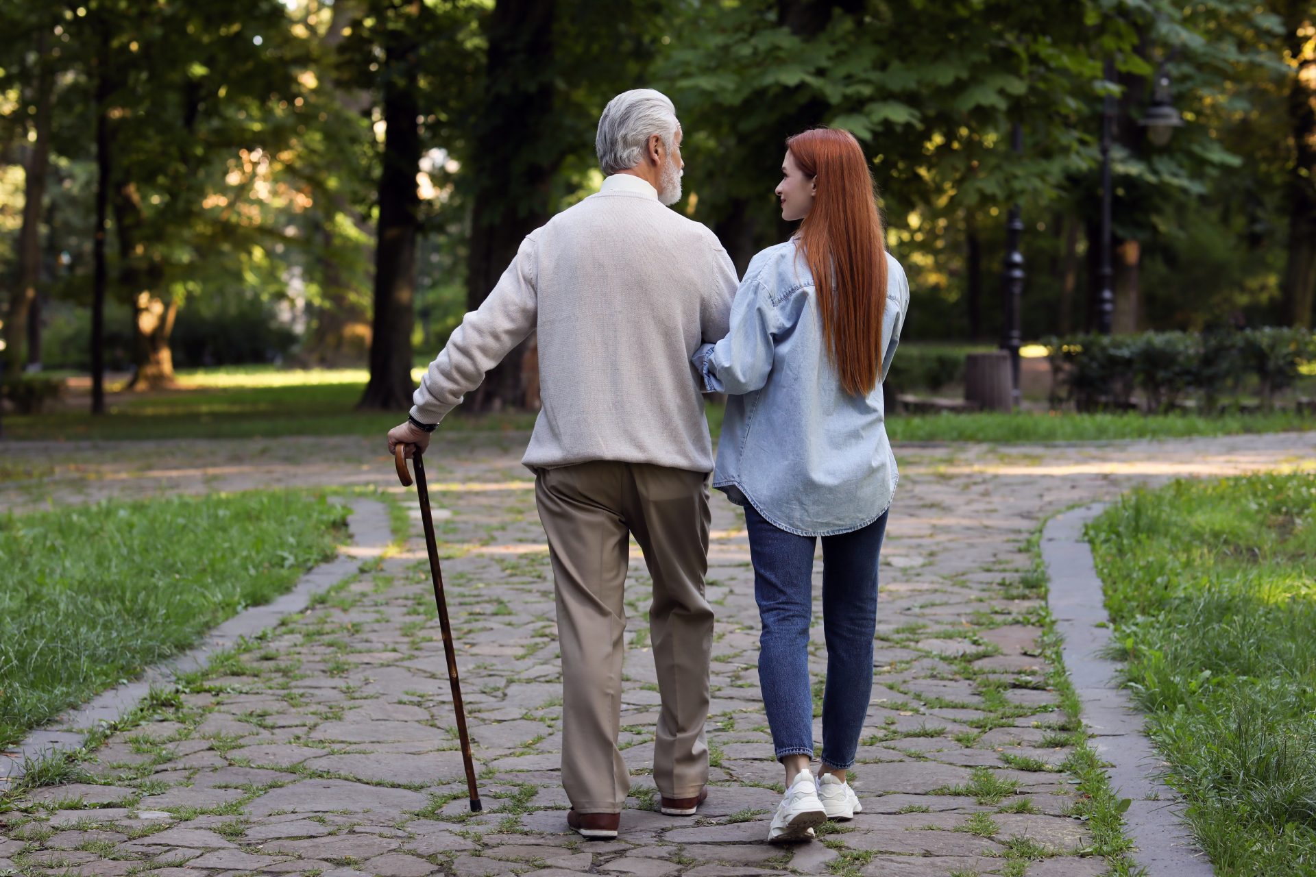 giovane donna accompagna anziano con bastone da passeggio