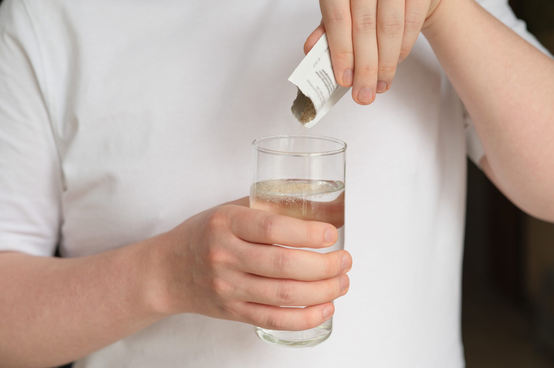 persona versa integratore di sali minerali in bicchiere d'acqua