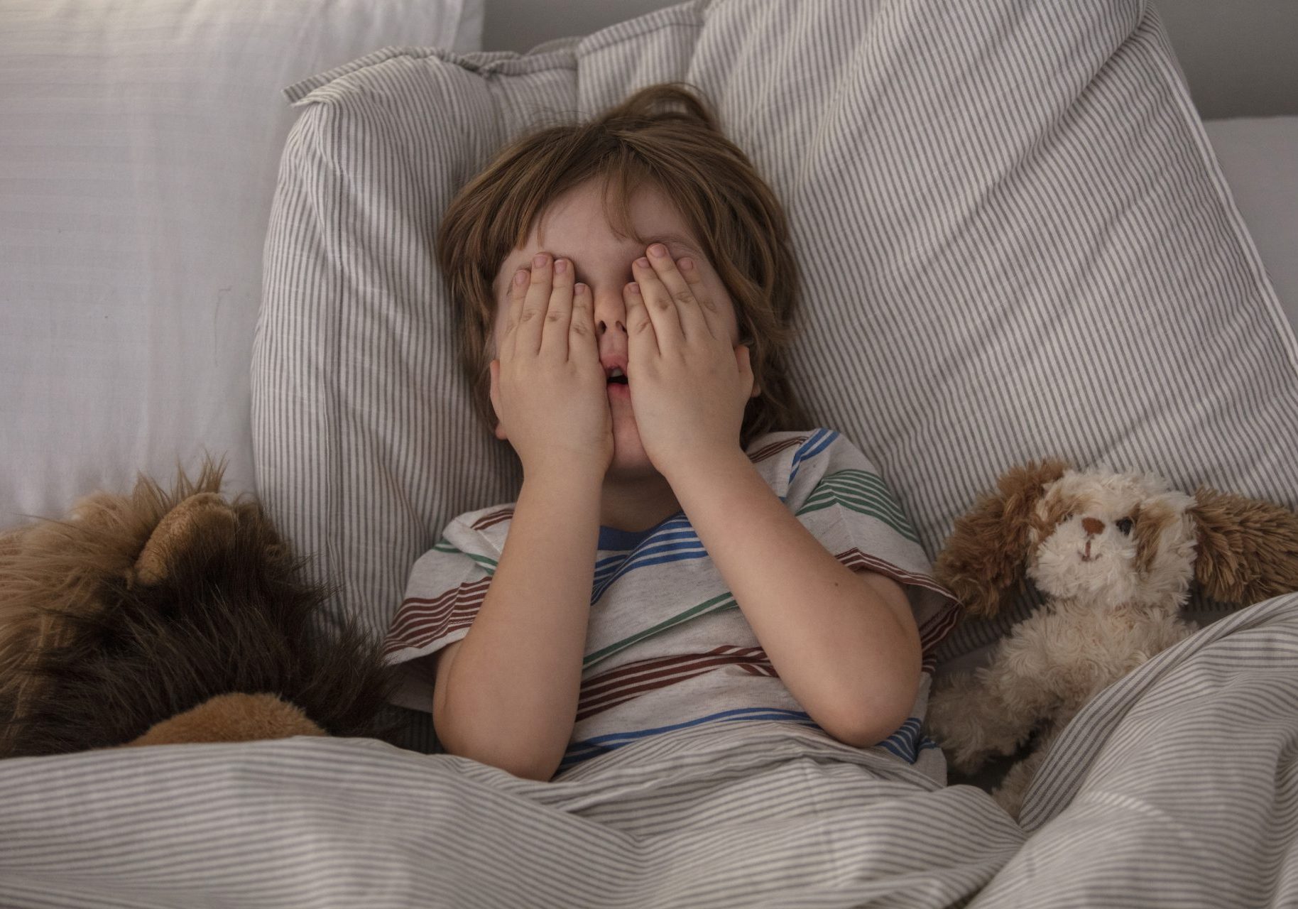 bambino impaurito a letto si copre gli occhi