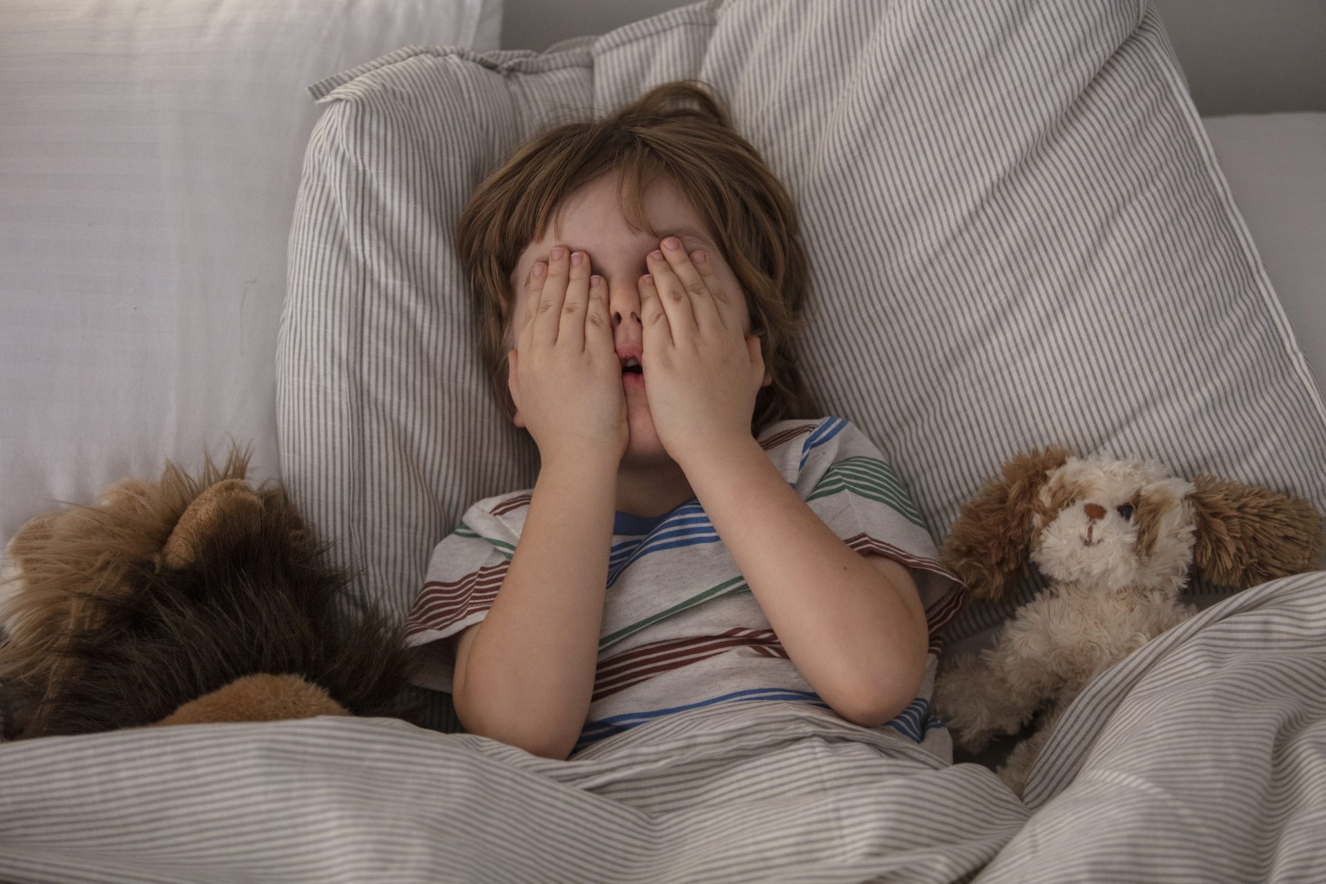 bambino impaurito a letto si copre gli occhi