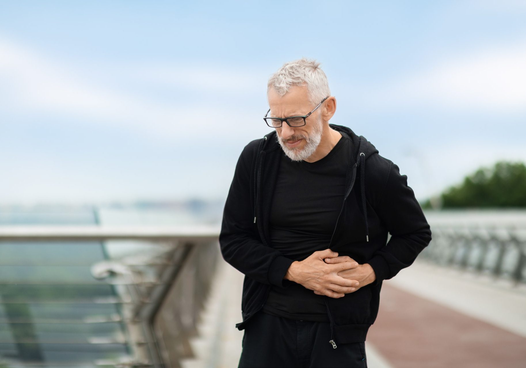 uomo all'aperto con dolore al lato sinistro dell'addome