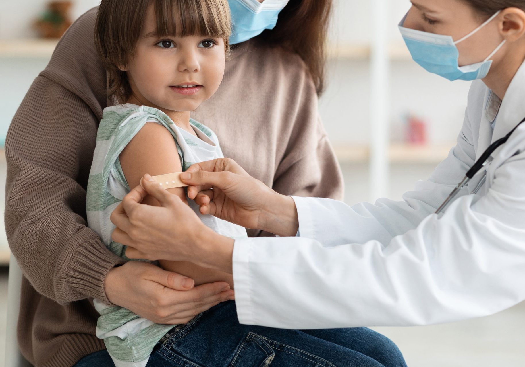 medico applica cerotto sul braccio di bambina dopo vaccino