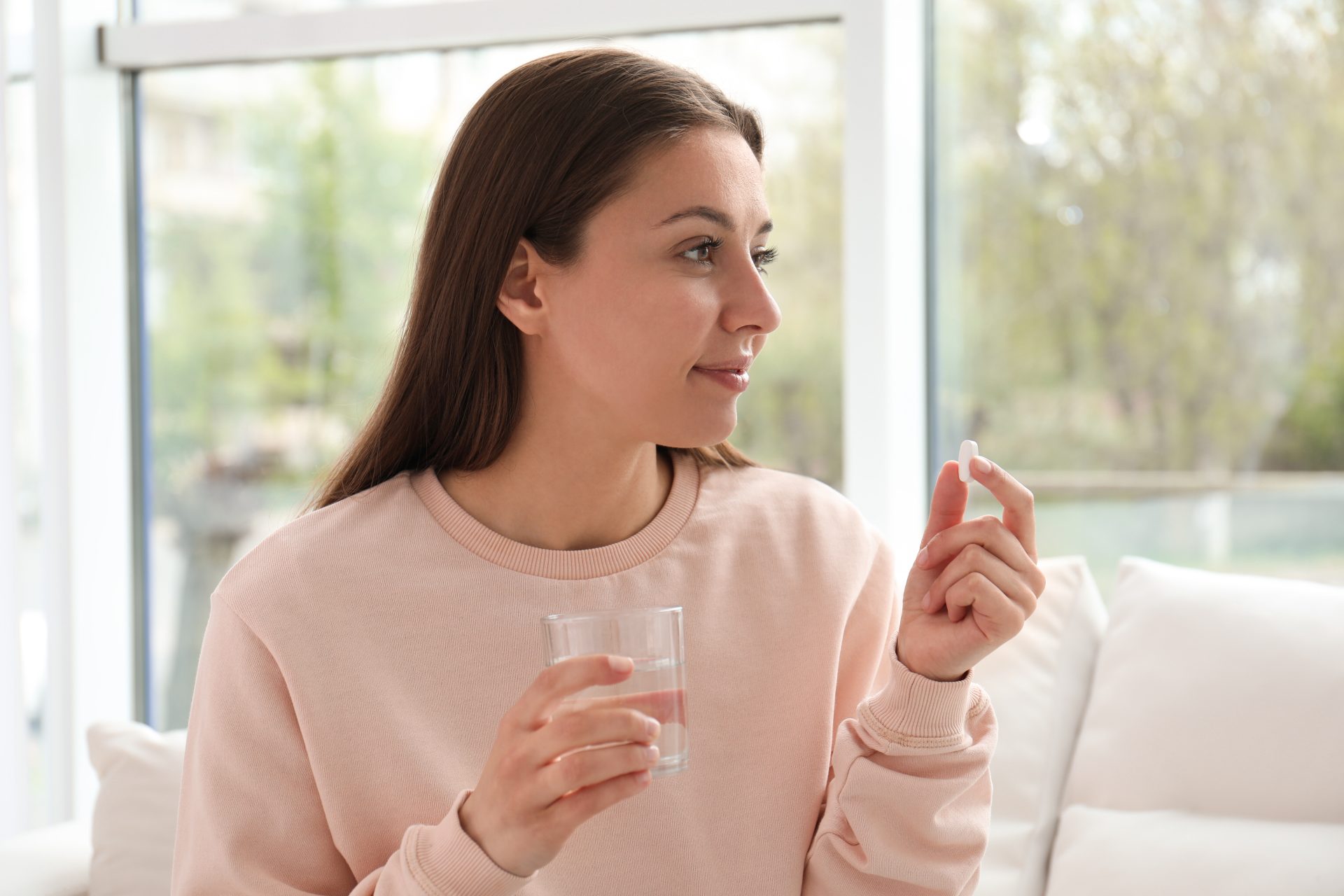 giovane donna assumere integratore con bicchere d'acqua
